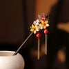 Un ensemble d'accessoires pour cheveux en bois de style chinois rétro avec des fleurs dorées et des perles rouges sur un bâto