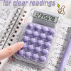 A clear plastic 8-digit wide screen calculator with purple buttons and scientific functions resting on a sheet of paper.
