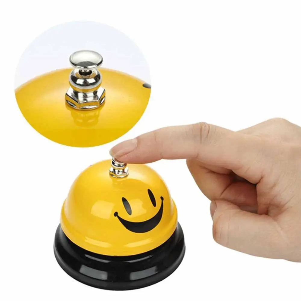 A hand is shown pressing a yellow metal service bell for desk or counter.