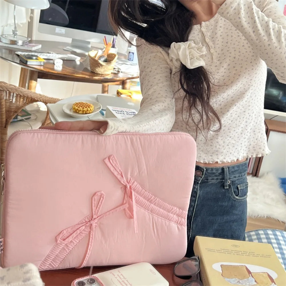 A pink ultra-thin laptop sleeve case is shown resting on a wooden table next to other items.