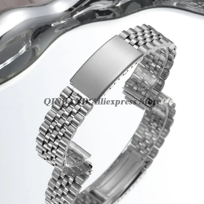 A close-up view of a polished stainless steel watch band with a folding clasp.