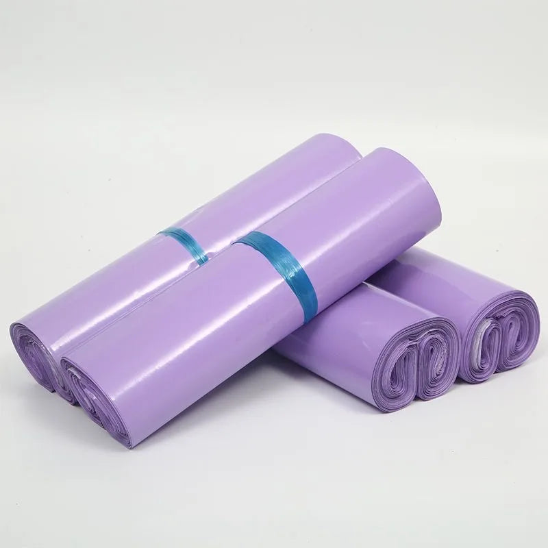 Purple waterproof self-adhesive courier mailer bags rolled up and stacked.