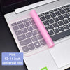 A pink silicone keyboard cover for a laptop is shown with a keyboard placed on the white laptop surface.