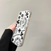A clear acrylic phone case featuring a black and white design with Chrome Hearts motifs, held by a hand.