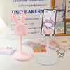 A pink rabbit mobile phone stand with a cute face design is shown next to a framed menu.