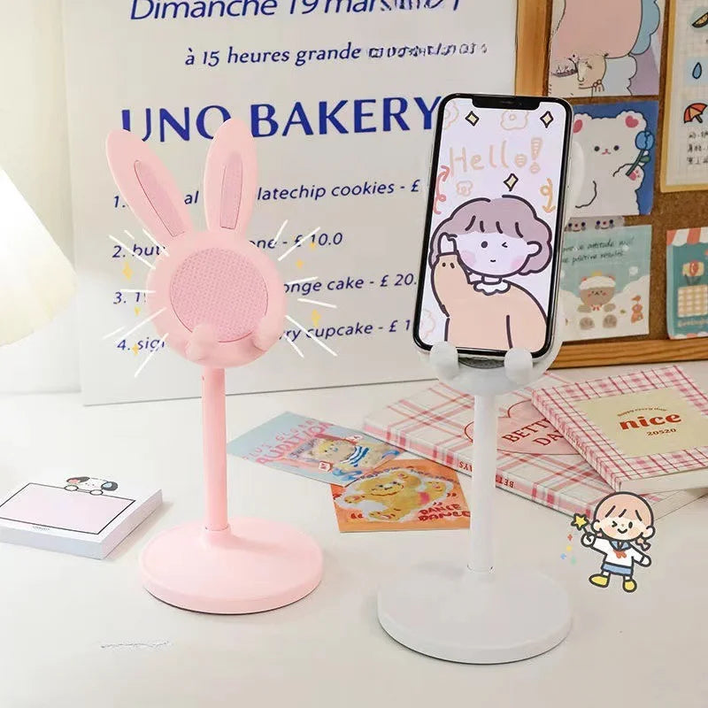 A pink rabbit mobile phone stand with a cute face design is shown next to a framed menu.