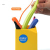 A yellow container holds various colored pen-shaped tools, including a lime green one, demonstrating a curved design.
