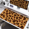 A large leopard print desk pad is displayed on a white desk next to a digital clock and a laptop.