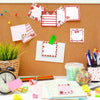 A collection of pink and red strawberry-shaped self-stick memo notes displayed on a corkboard.
