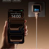 A hand holds an iPhone charging on a wall charger, with icons for various Apple products displayed above.