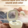 A white mini Bluetooth earphone case and earphones are shown resting on a rocky surface with a mountainous background.