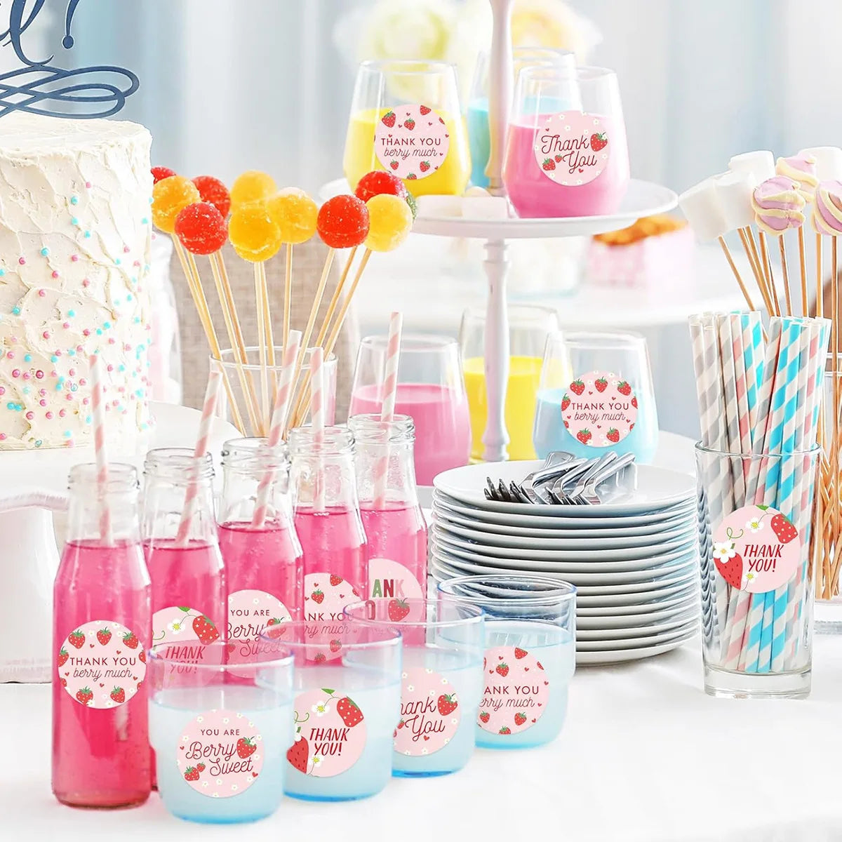 A display of pink and yellow adhesive stickers on wooden skewers arranged in various glass jars and on a white platter.