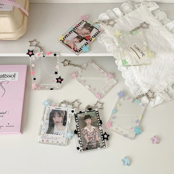 A collection of acrylic photocard holders and pendants with various charms arranged on a white surface.