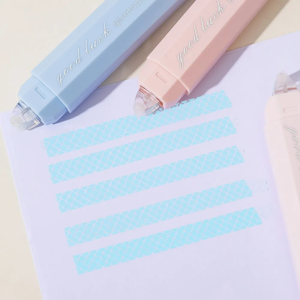 Two gradient double-sided tape pens in light blue and pink resting on a white sheet of paper.