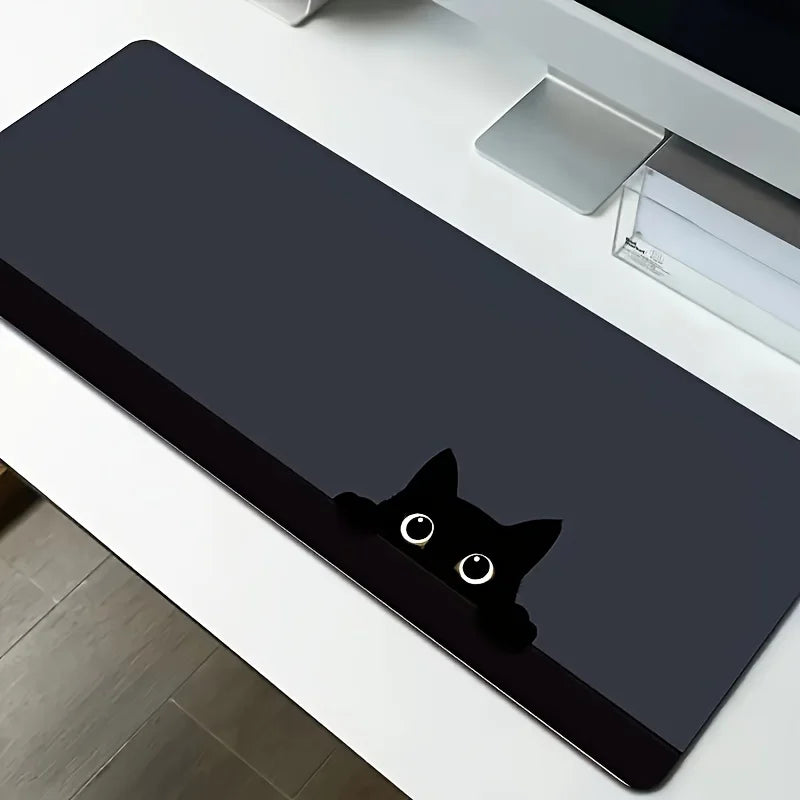 A black cat silhouette mouse pad is placed on a white desk mat next to a silver electronic device.