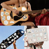Eine Person spielt eine akustische Gitarre, dekoriert mit Vinylstickern, vor dunklem Hintergrund.