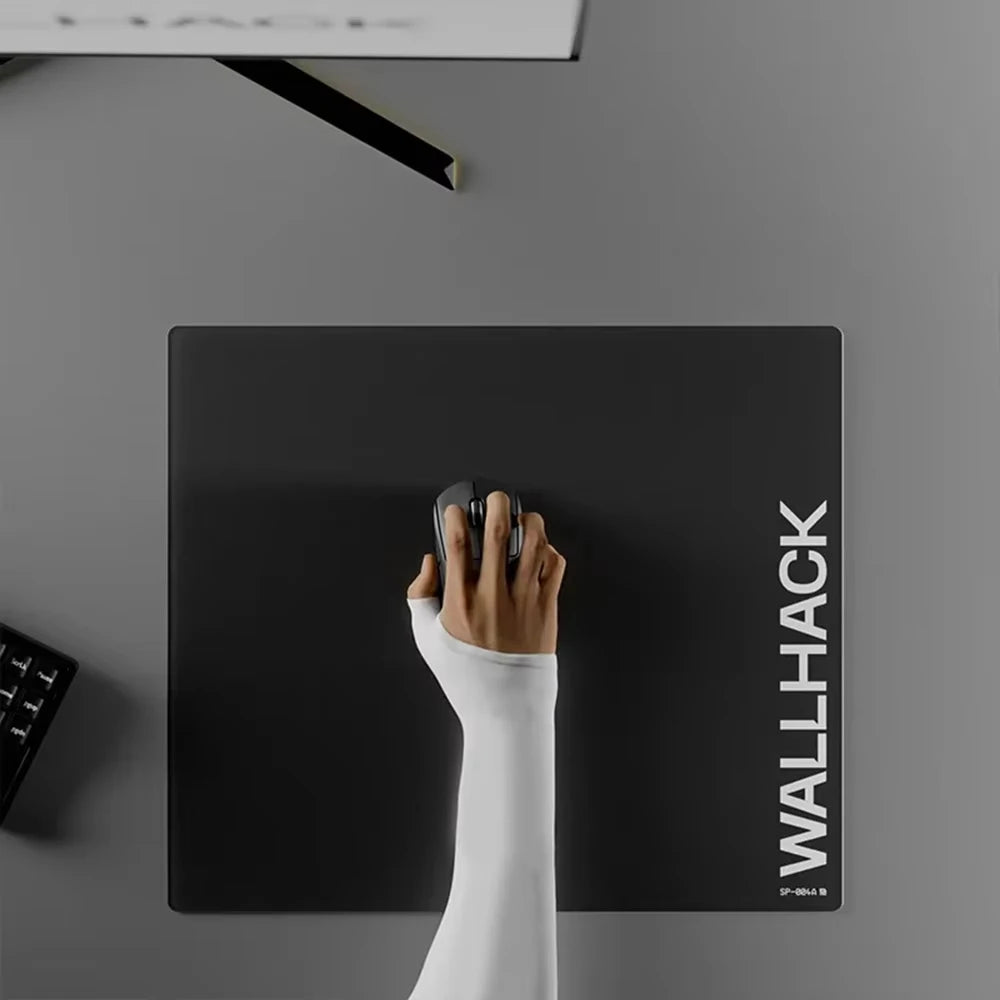 Un tapis de souris en verre trempé noir est fixé sur un mur gris, affichant le texte latéral WALLHACK.