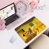 A yellow and brown dog illustration on a gaming mouse pad next to a laptop and pink stationery.
