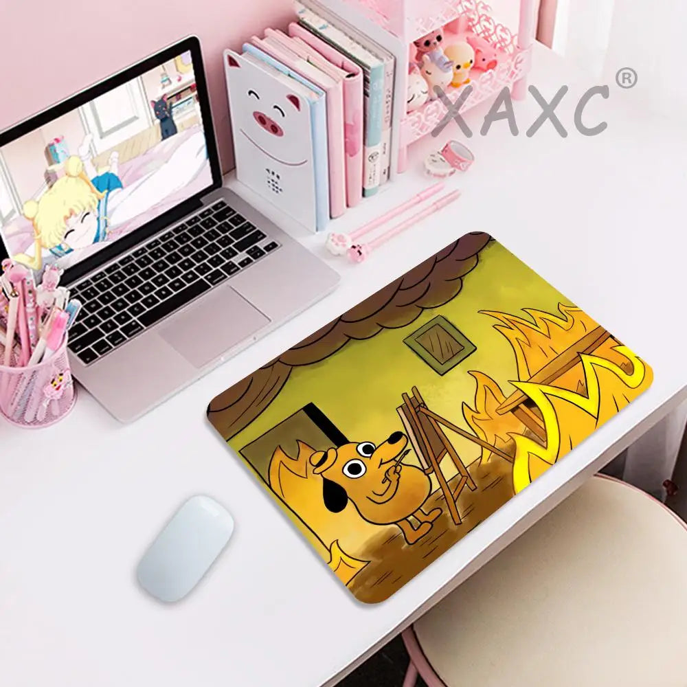 A yellow and brown dog illustration on a gaming mouse pad next to a laptop and pink stationery.