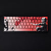 A close-up of mechanical keycaps featuring a raven and sakura theme with red and white accents.
