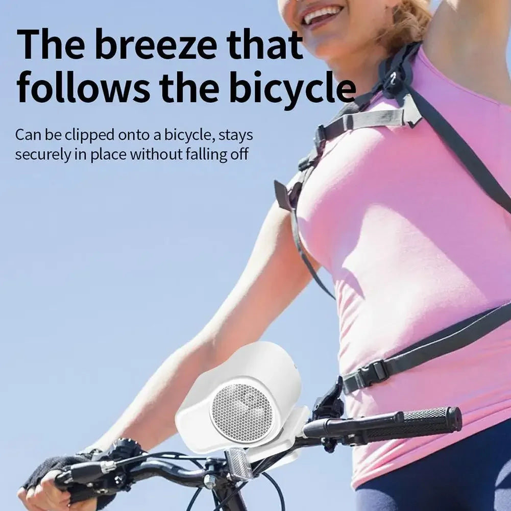 A woman is using a portable clip-on fan attached to a bicycle, demonstrating its secure fit.