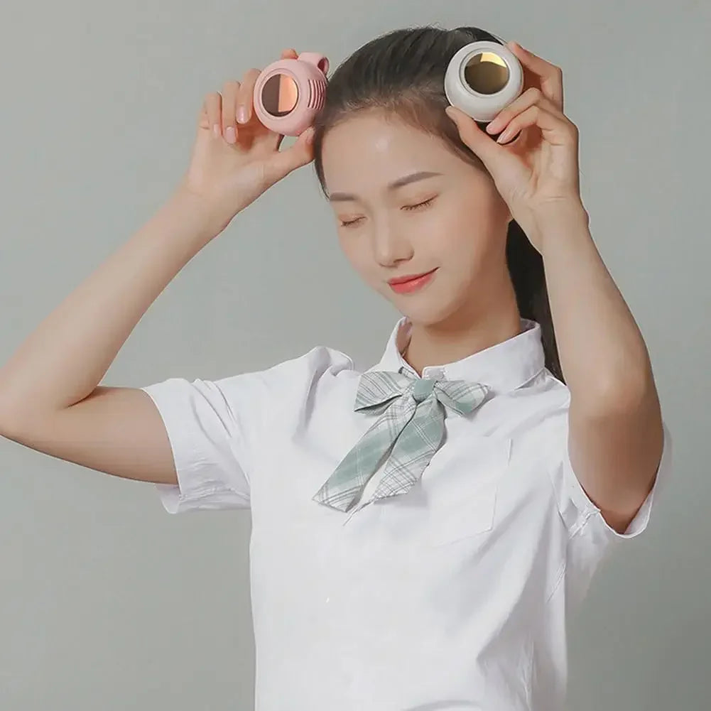 A woman holds a pink portable mini blade-less electric fan near her face.