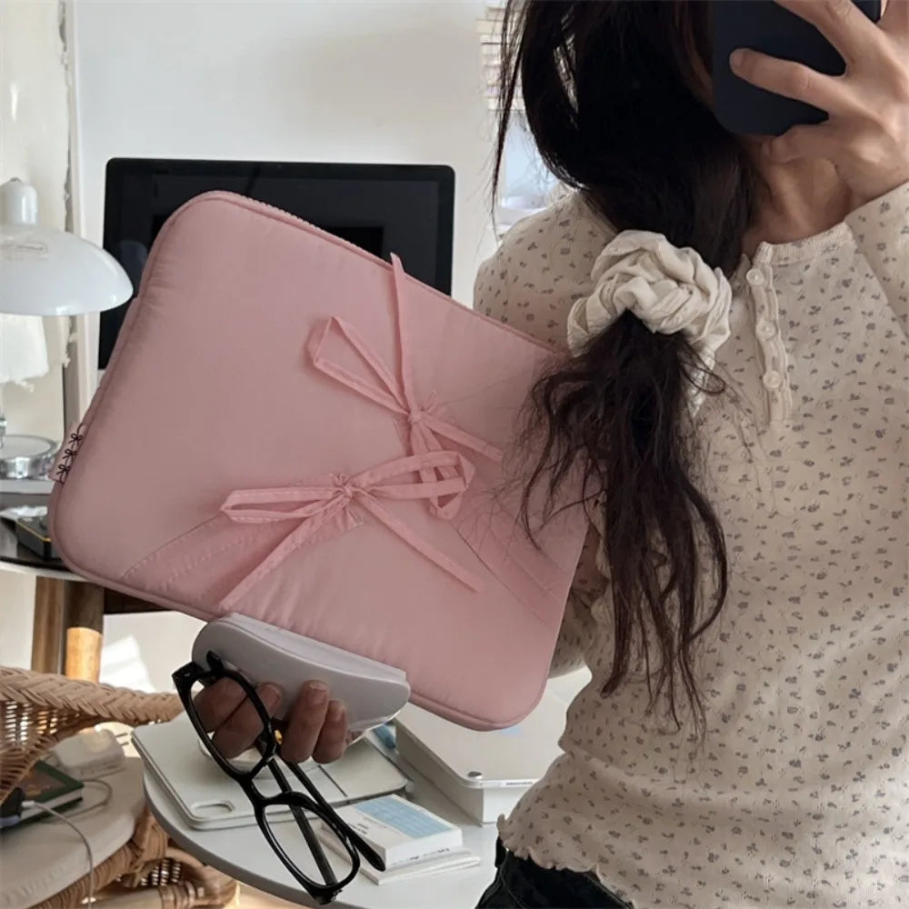 A pink ultra-thin laptop sleeve case is shown next to a woman's hand and some glasses.