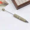 A silver pen with a rhinestone-encrusted tip and a decorative gold-colored ball on the end.
