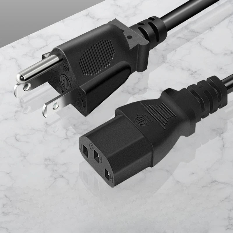 A black universal power cord adapter with a connector and cable lying on a white marble surface.