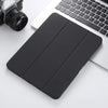 A black retro marbling skin for an iPad Pro placed next to a silver camera and a white laptop keyboard.