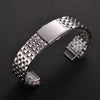 A stainless steel watch band with a textured metal link and a folding safety clasp is shown on a dark background.