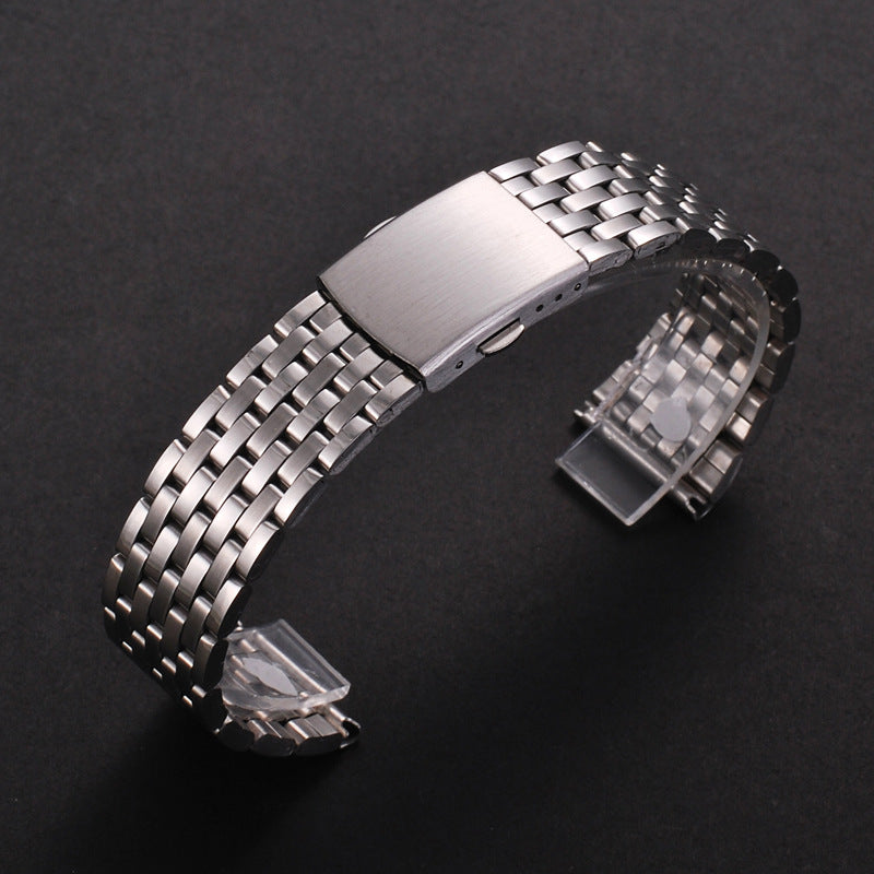 A stainless steel watch band with a textured metal link and a folding safety clasp is shown on a dark background.
