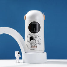 A white automatic electric pencil sharpener with a round viewing window and educational diagrams sits on a white base.