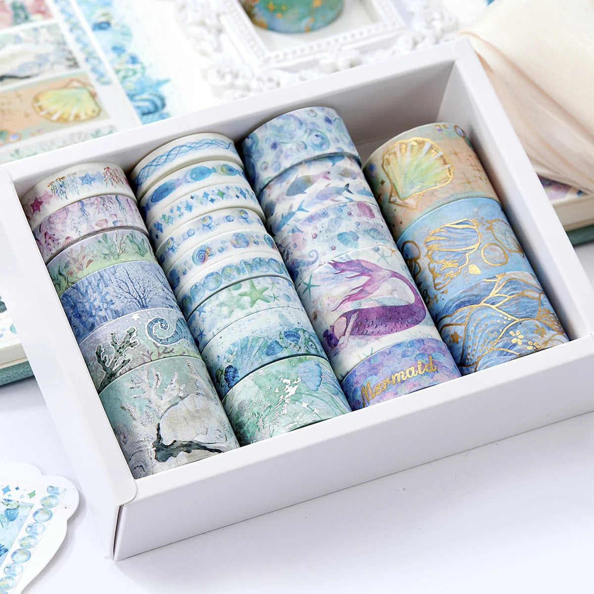 A box of oil painting themed decorative washi tape rolls in various colors and designs.