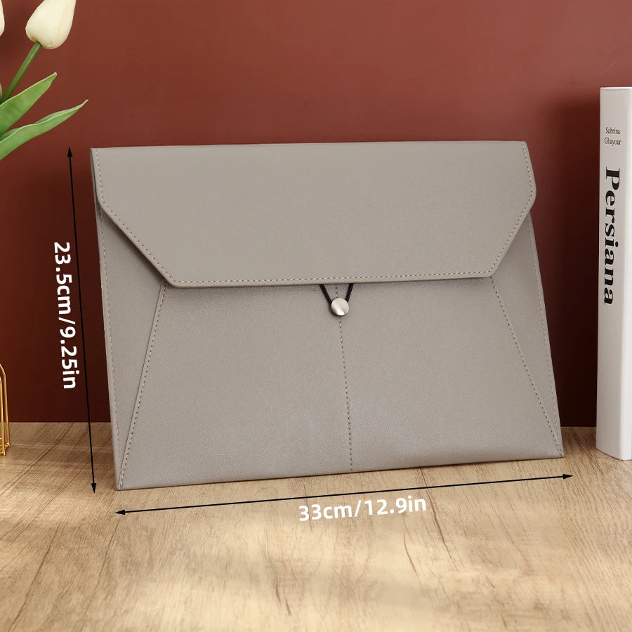 A light gray leather document organizer bag with a flap closure shown on a wooden surface.