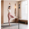 A woman performing a yoga pose using a floor stand mode magnetic phone tripod for full-body shots.