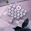 Eine Sammlung personalisierter Schmetterling-Keycaps in einer klaren Kunststoffschale