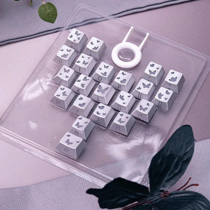 Eine Sammlung personalisierter Schmetterling-Keycaps in einer klaren Kunststoffschale
