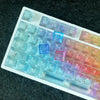 A close-up view of a rainbow colored PC keycap set for a mechanical keyboard displayed on a dark surface.