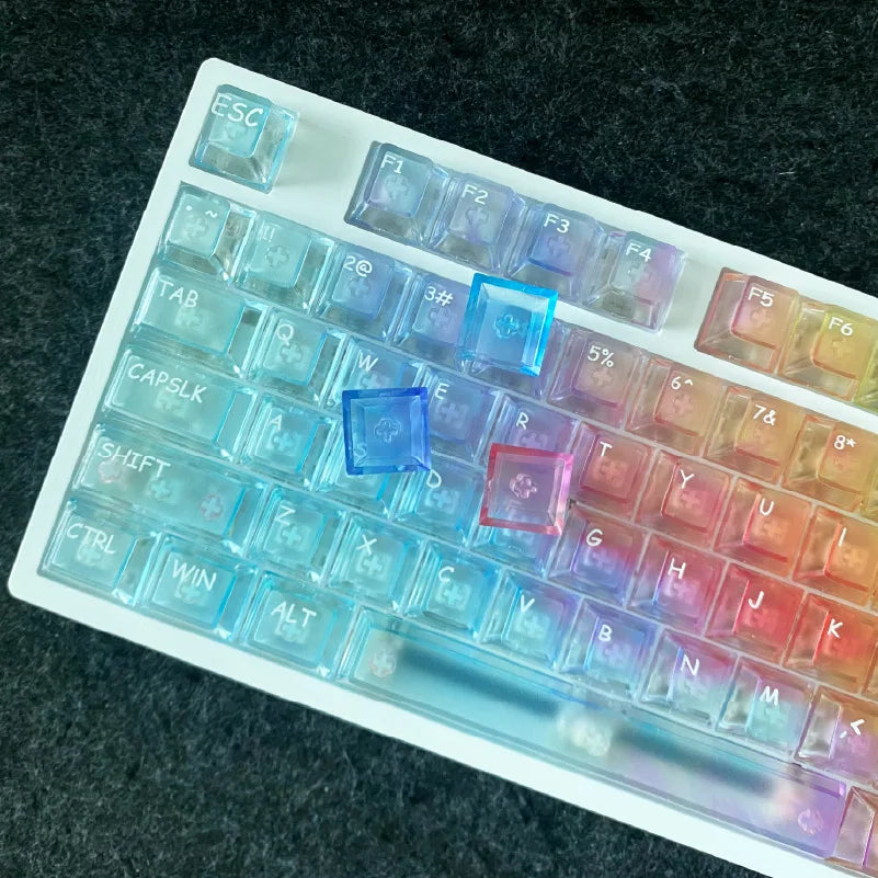 A close-up view of a rainbow colored PC keycap set for a mechanical keyboard displayed on a dark surface.