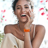 A smiling woman wearing an orange sport hook and loop watch strap.