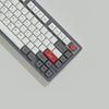 A close-up view of a gray mechanical keyboard with retro NES style PBT keycaps and red accents.