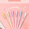 A collection of pen-shaped dot glue in various pastel colors, including pink, yellow, and blue, displayed on a pink backgroun