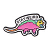 Broche émail représentant une créature stylisée jaune et verte avec le texte STAY WEIRD.