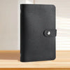 A black reusable envelope money saving challenge binder with a silver clasp on a wooden surface.