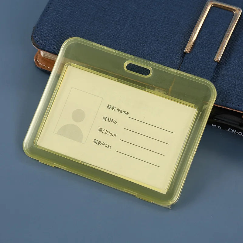 Porta de identificación de plástico transparente con inserto amarillo sobre una carpeta o cuaderno azul oscuro.