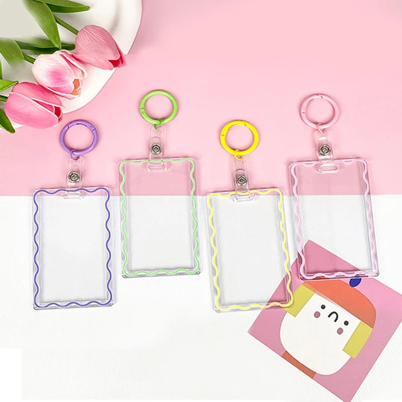 Four clear acrylic card holders with colorful keychains displayed on a pink background.
