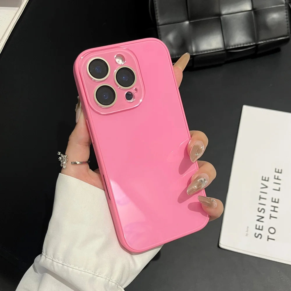 A pink iPhone in a glossy tempered glass shockproof case is held by a hand against a black background.