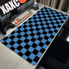 A black and blue checkered desk mat is placed on a wooden desk next to a keyboard and gaming controller.