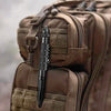 A close-up view of a brown tactical self-defense pen with a glass breaker tip inside a padded tactical bag.